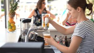 Una mujer llena un vaso de cerveza en un bar en Easyatent Camping Valkanela, en Vrsar
