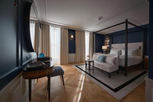 a bedroom with a bed and a table and a desk at GA Palace Hotel & Spa, a XIXth-Century Villa in Porto