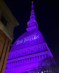una torre iluminada en púrpura frente a un edificio en Torino Casa Maria - 2 Bedroom Apartment, en Turín