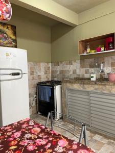 a kitchen with a white refrigerator and a stove at Suíte com cozinha para casal in Araruama