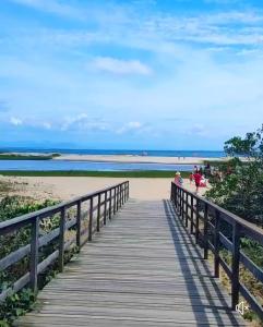 un paseo marítimo de madera hasta la playa con gente en él en Casa Praia Ubatuba Sâo Francisco do Sul 3 quartos en São Francisco do Sul