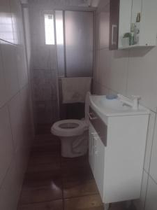 a white bathroom with a toilet and a sink at Casa Praia Ubatuba Sâo Francisco do Sul 3 quartos in São Francisco do Sul