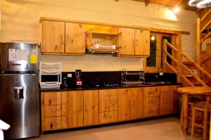 een keuken met houten kasten en een roestvrijstalen koelkast bij Casa Kambana en Vilcabamba in Loja