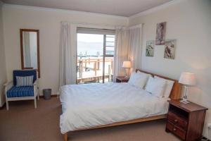 1 dormitorio con cama, ventana y silla en New Listing- 33 Laguna Grove on the water, en Knysna