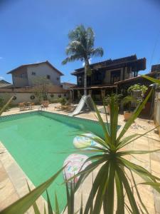 a swimming pool in a house with a palm tree at Suíte com cozinha para casal in Araruama