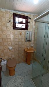 a bathroom with a toilet and a sink and a shower at Acomodação Ruth Guaratuba in Guaratuba