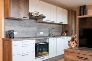a kitchen with white cabinets and a sink and a tv at Piz Aich Natur Chalet Panorama in Avelengo