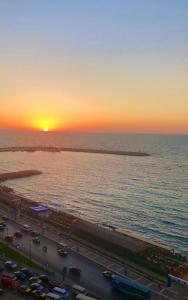 a sunset over a highway and the ocean with cars at Salvatore Rooms -Corneish Street in Alexandria