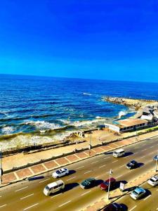 a road with cars parked next to the ocean at Salvatore Rooms -Corneish Street in Alexandria