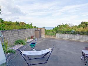 un patio con 2 sillas y una hamaca en 太平洋を見渡せる海浜リゾート貸切観海荘チャオ, en Momiyama