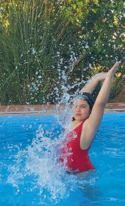 una mujer en una piscina rociándose con agua en Cabañas Tranquera 8 en Chascomús