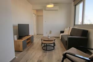a living room with a couch and a tv at Phaedrus Living Coral Suites Bliss in Larnaka