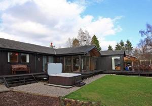 a black house with a backyard with a lawn at Ptarmigan Lodge Nethy Bridge in Nethy Bridge