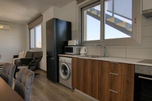 a kitchen with a refrigerator and a sink and a dishwasher at Phaedrus Living Coral Suites Bliss in Larnaka