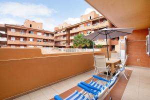 a balcony with a table and chairs and an umbrella at Beach Front Apartment Puertito in Güimar