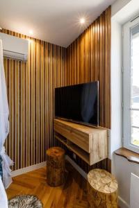 a living room with a flat screen tv on a wooden wall at Proche Paris - Style Bali 350 m gare Mantes in Mantes-la-Jolie