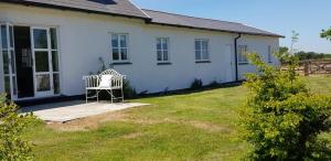 a white house with a bench in the yard at Seahorse Cottage in Helston