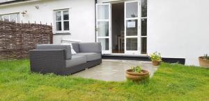 a couch sitting on a lawn in front of a house at Seahorse Cottage in Helston