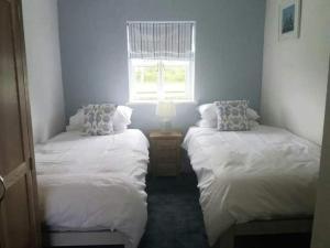 two twin beds in a room with a window at Seahorse Cottage in Helston