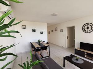 a living room with a table and a clock on the wall at Appartement refait à neuf, climatisé avec vue mer et montagne, avec place de parking privative in Saint-Cyprien