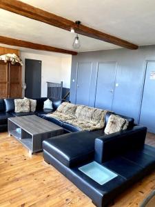 a living room with a black leather couch and a table at La Ferme in Ascq