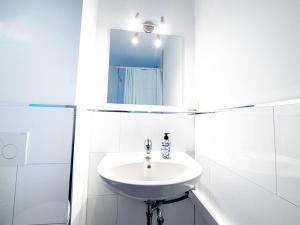 ein weißes Badezimmer mit einem Waschbecken und einem Spiegel in der Unterkunft Work & stay in Ahrensburg in Ahrensburg