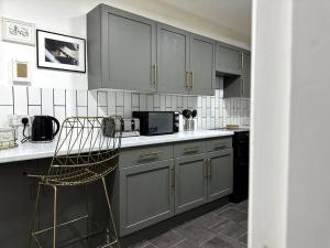 a kitchen with gray cabinets and a chair in it at Luxury 3 Bed Home In London in London