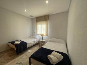 due letti in una piccola stanza con una finestra di Apartamento Palmones a Cordoba
