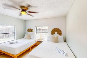 two beds in a room with a ceiling fan at Beach Life in Panama City Beach