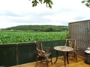duas cadeiras e uma mesa num alpendre com um campo de milho em Amelyah Studio Cottage in Beautiful Countryside em Winscombe