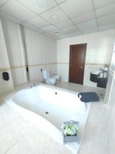 a large white bath tub in a bathroom with a toilet at SKY High Stays in Dubai