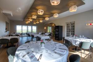 una sala da pranzo con tavoli e sedie bianchi di Hôtel & restaurant Le Meysset a Sarlat-la-Canéda
