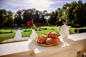 a plate of pastries and a vase with a rose at Château de la Grange Moreau in Vallon-sur-Gée