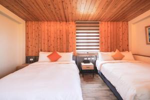 2 camas en una habitación con paredes de madera y ventana en Chill hill cottage en Taiping