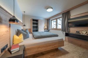 ein Schlafzimmer mit einem großen Bett und einem TV in der Unterkunft Bergmomente Apartments in Sölden