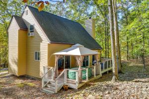 una pequeña casa amarilla con porche y sombrilla en Forest-View Poconos Cabin with Hot Tub!, en East Stroudsburg