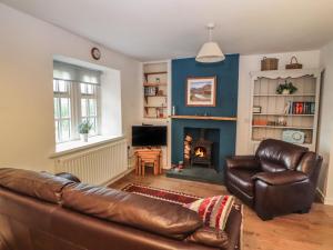een woonkamer met een bank en een open haard bij Kestrel Cottage in Keswick