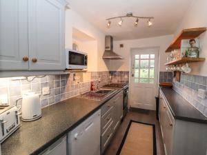 een keuken met witte kasten en zwarte aanrechtbladen bij Kestrel Cottage in Keswick