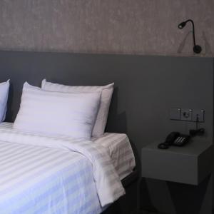 a bed with white sheets and a lamp on a night stand at Fhandika Boutique Inc. in Geutieue