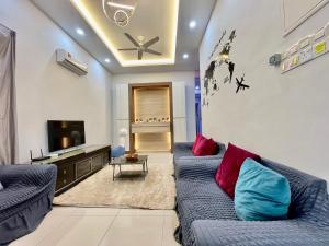 ein Wohnzimmer mit 2 blauen Sofas und einem TV in der Unterkunft Home36#8pax#4bedroom#NearAeonAlma#Mcd in Bukit Mertajam