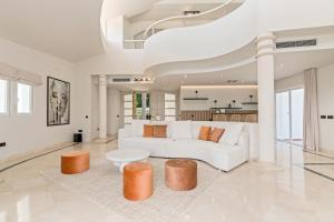 a white living room with a white couch and stool at All About La Redonda Villa in Estepona