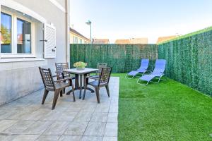 een terras met stoelen, een tafel en gras bij Gîte La Vapillone Paris Marne-la-Vallée in Serris