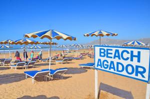 Caribbean Village Agador - All inclusive في أغادير: وضع علامة على الشاطئ مع الكراسي والمظلات
