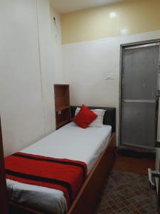 a bedroom with a bed with a red pillow on it at Hotel Knight Inn Airport in Guwahati