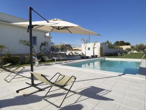 a pair of chairs and an umbrella next to a swimming pool at Villa Rita in Marsala