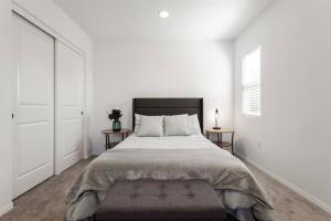 a white bedroom with a large bed and two tables at Entire Guesthouse for Rent in San Bernardino in San Bernardino