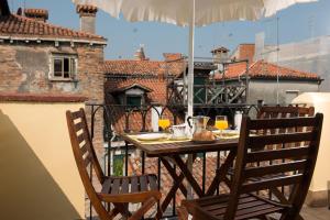 una mesa con 2 sillas y una sombrilla en el balcón en Rialto, en Venecia
