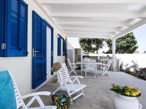 a patio with blue doors and white chairs and a table at Spuma di Mare - Riccio in San Vito lo Capo