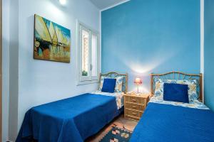 een blauwe slaapkamer met 2 bedden en een raam bij Casa Marsala in Marsala