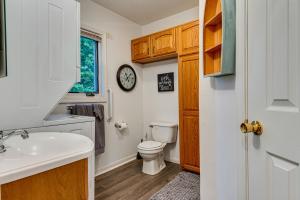 a bathroom with a toilet and a sink and a clock at Riverfront Brookston Retreat w/ Deck & River Tubes in Brookston